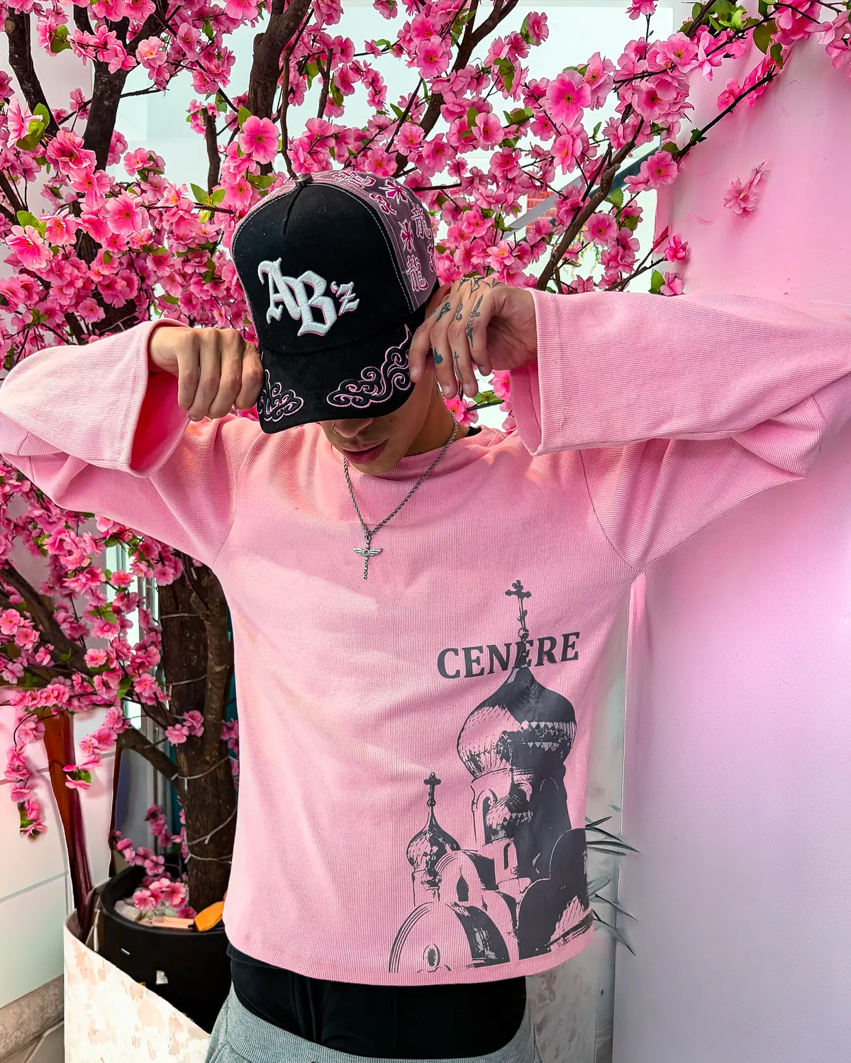 Longsleeve rosa con estampado arquitectónico, frente a un árbol en flor.