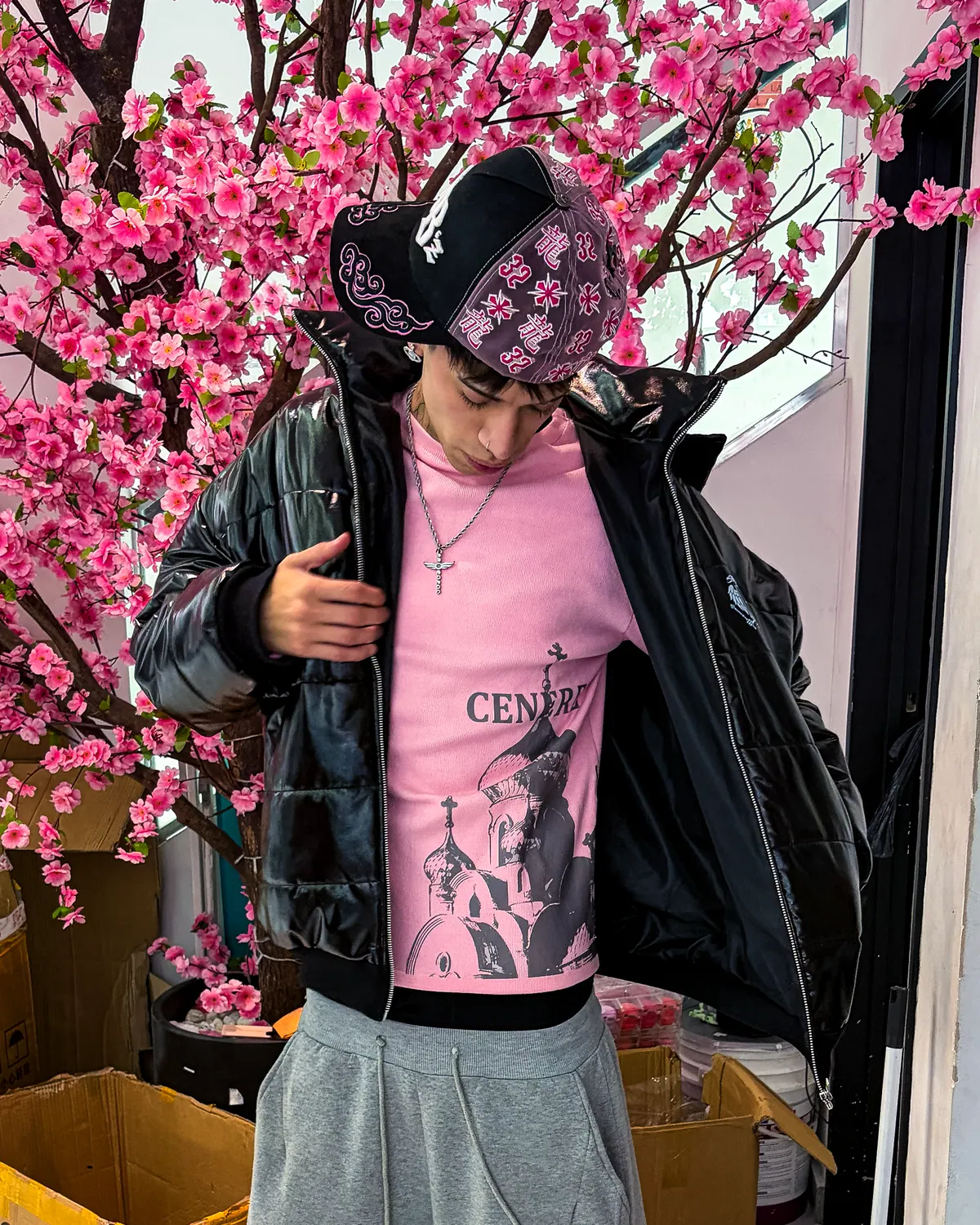 Longsleeve rosa y puffer negra frente a un árbol en flor.