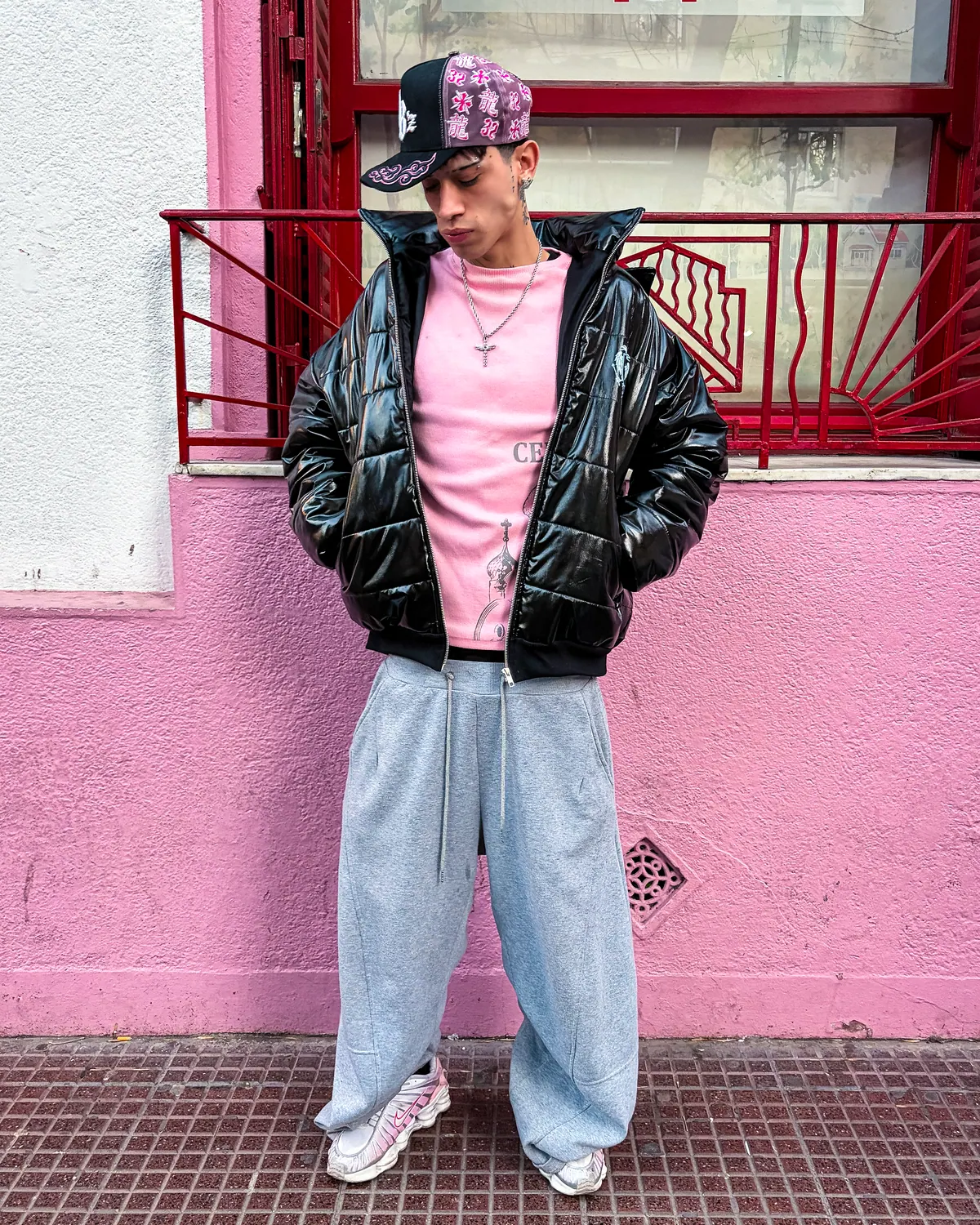 Puffer negra y longsleeve rosa frente a una pared rosa.